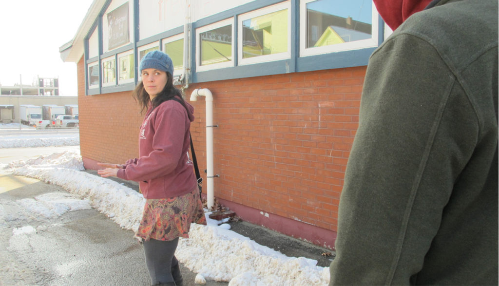 Woman on the street looking over her shoulder at a barely seen person following her